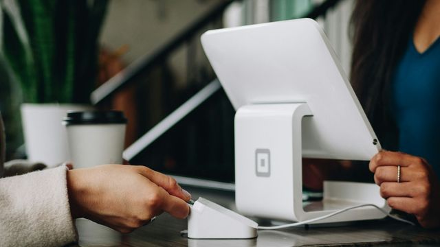 A customer paying by card at a tablet on a shop counter